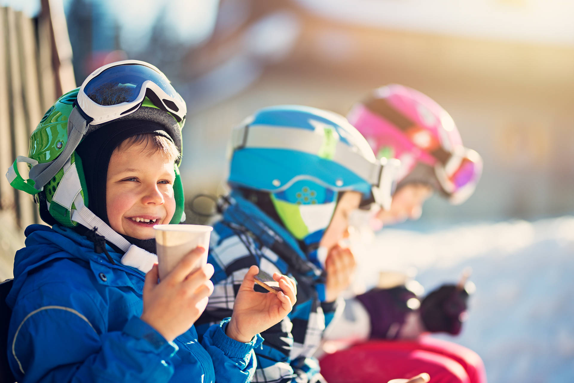 Children skiing on a winter day. Kids are taking a break in skiing and having some hot tea and cookies.
